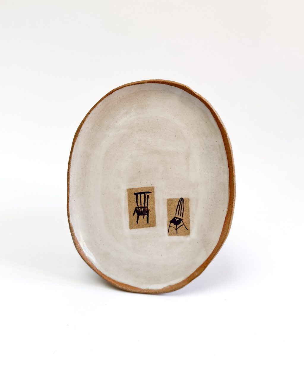 Ceramic plate with a painted chair design and white-washed glaze