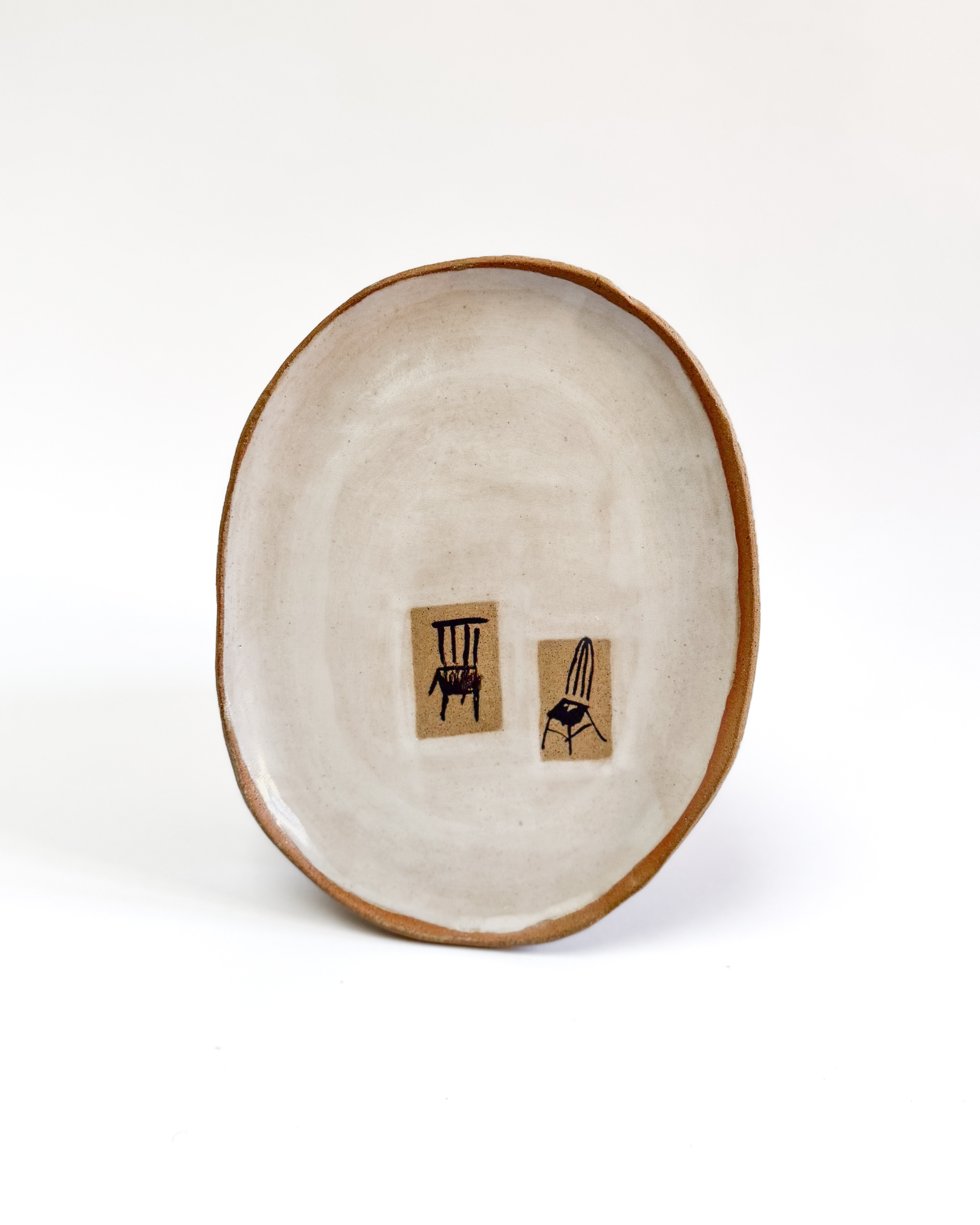 Ceramic plate with a painted chair design and white-washed glaze