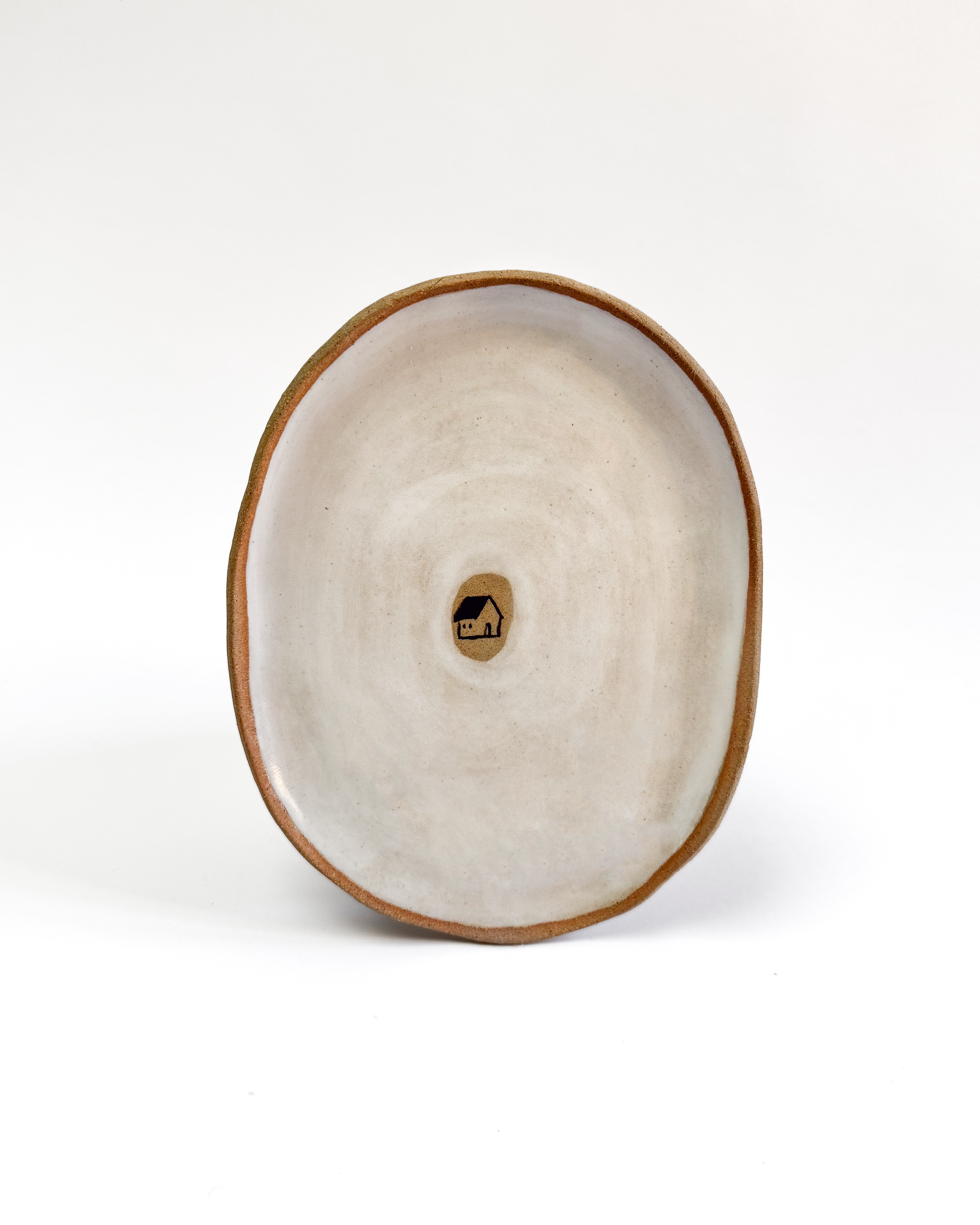 Ceramic plate with a painted house design and white-washed glaze