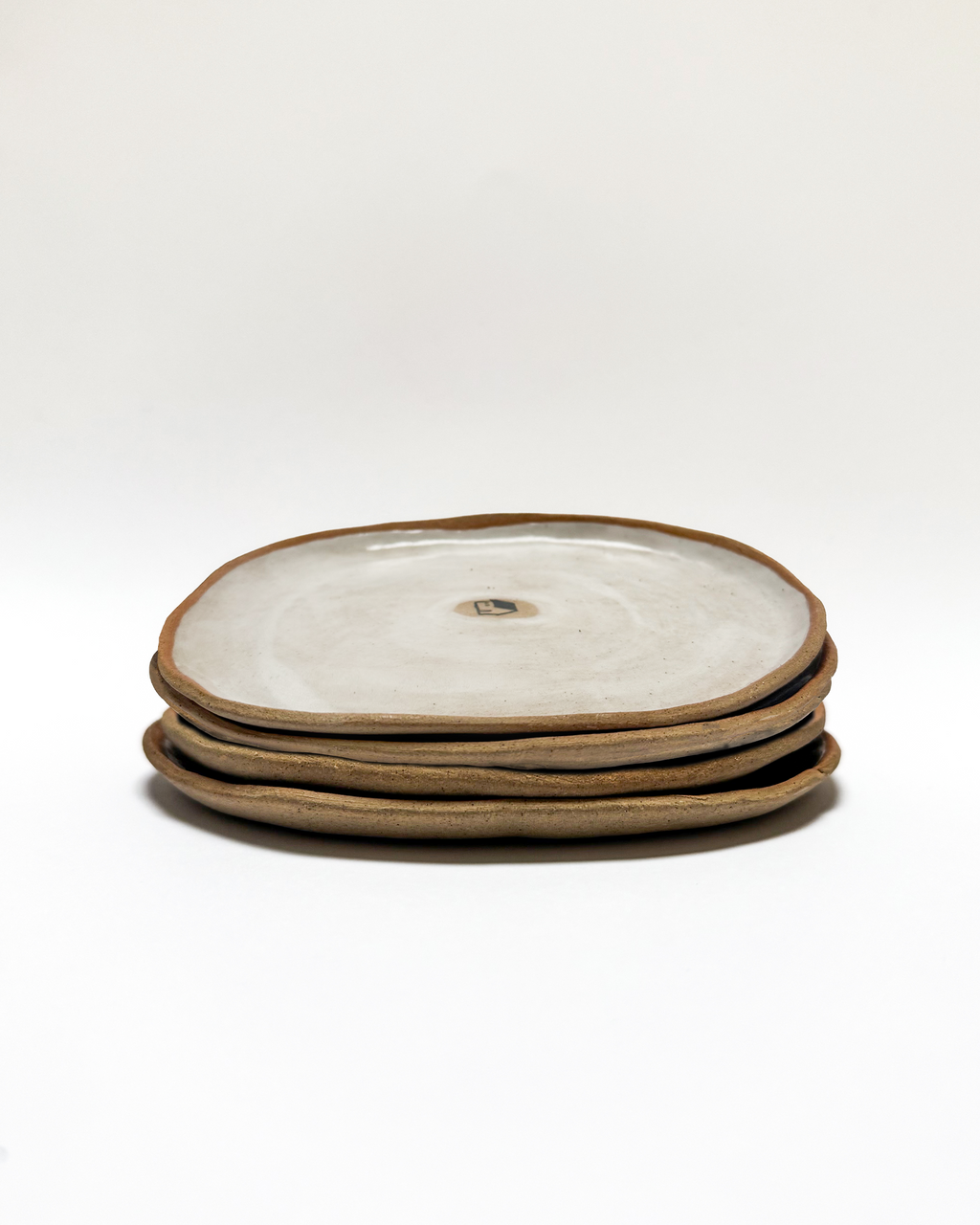 Stack of ceramic plates with a painted house motif on a white background