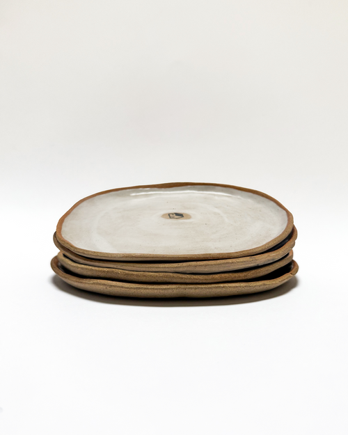 Stack of ceramic plates with a painted house motif on a white background